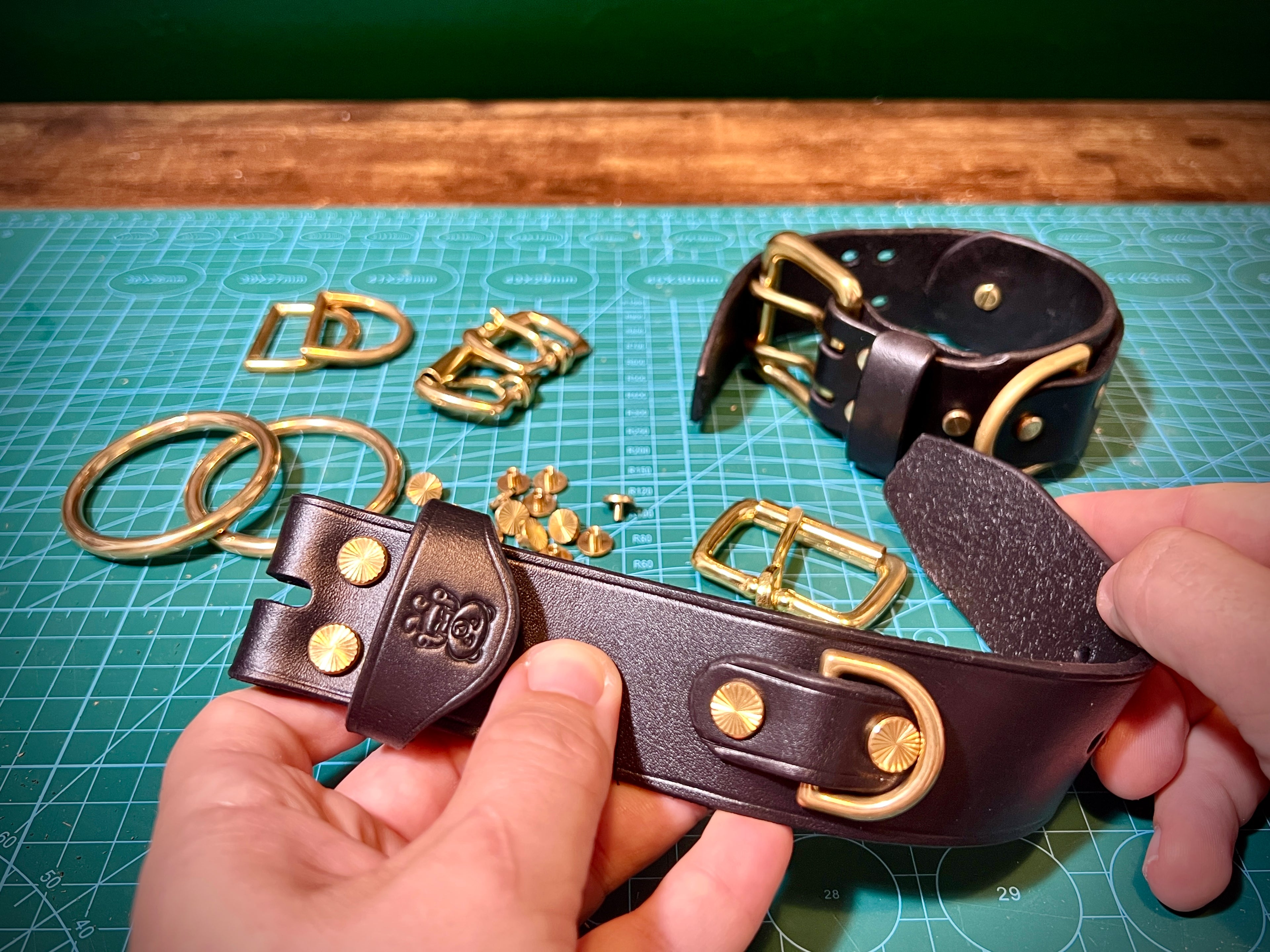 Black leather belt with gold buckles on a green cutting mat
