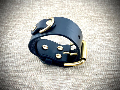 Black leather bridle bit with gold hardware on a textured gray background