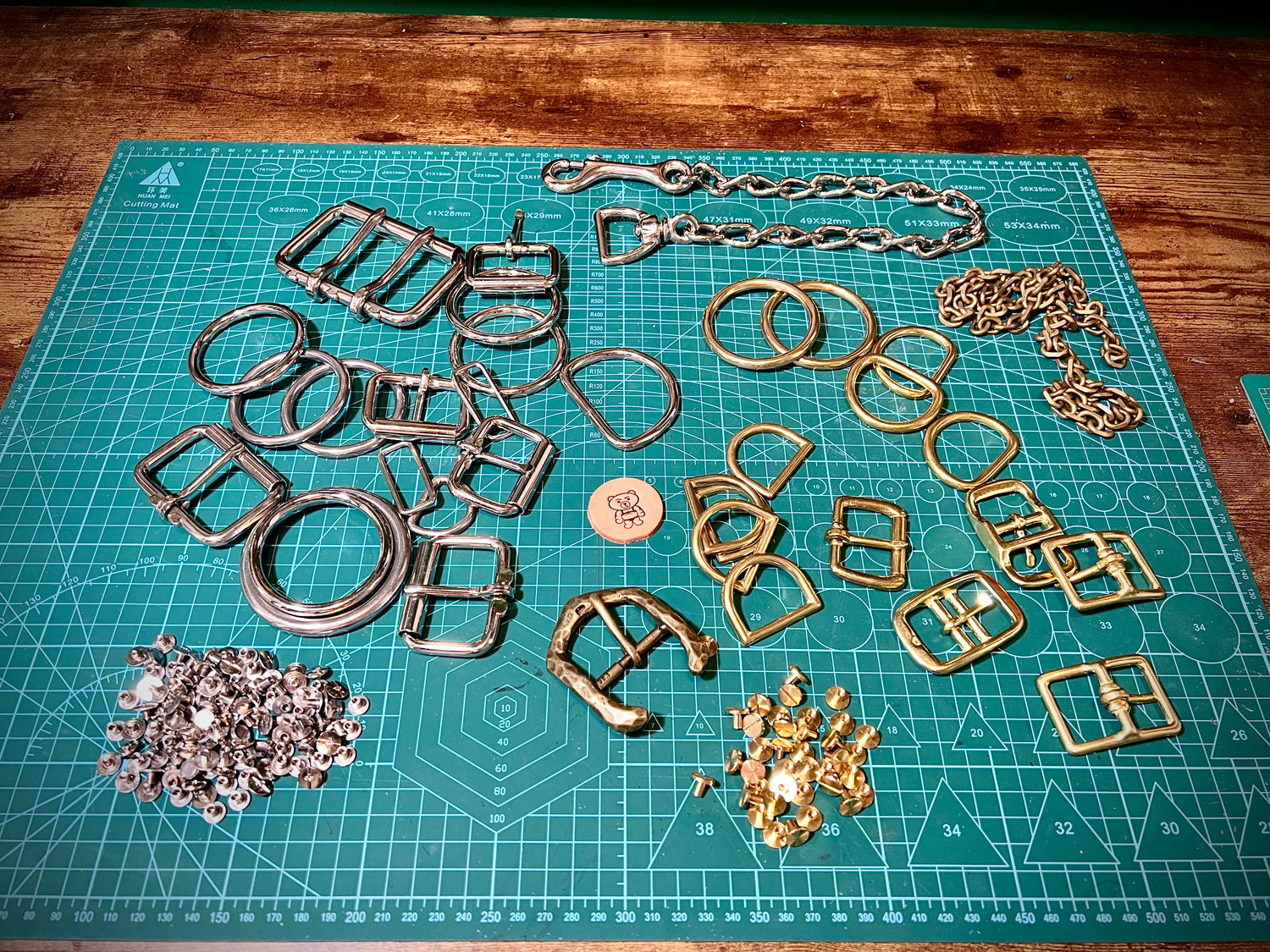 Collection of metal buckles and chains on a cutting mat