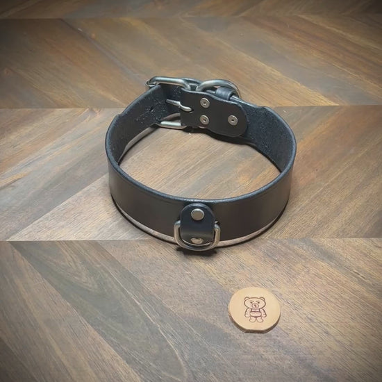 Demonstrating the functional flexibility and hardware locking action of a 1.75" black leather collar with nickel-plated steel hardware.