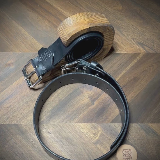 Manual demonstration unbuckling connected black leather restraint belts.
