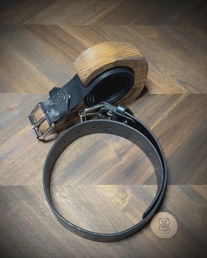 Manual demonstration unbuckling connected black leather restraint belts.