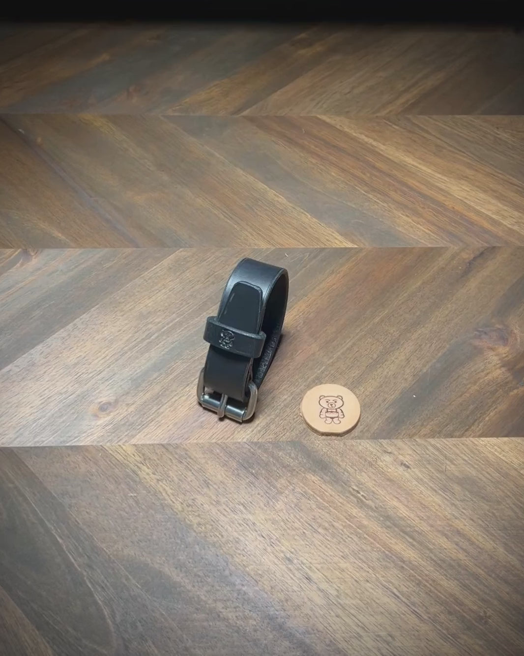 Hand-manipulating a black leather wrist cuff to demonstrate strap flexibility and steel roller buckle unfastening tracking.
