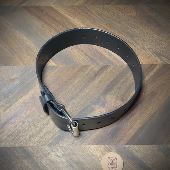 Manual demonstration unbuckling a heavy 1.75" black leather restraint belt.