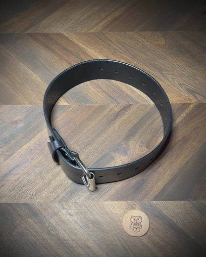 Manual demonstration unbuckling a heavy 1.75" black leather restraint belt.