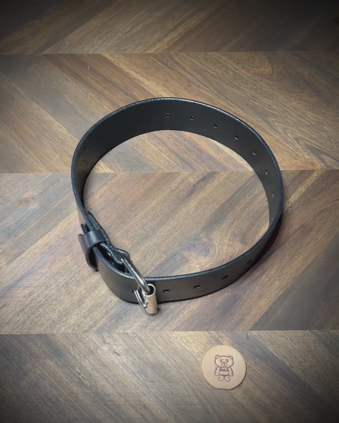 Manual demonstration unbuckling a heavy 1.75" black leather restraint belt.