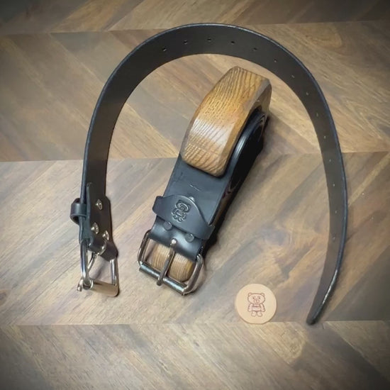 Manual demonstration buckling a heavy 1.75 inch black leather restraints through a steel roller closure.