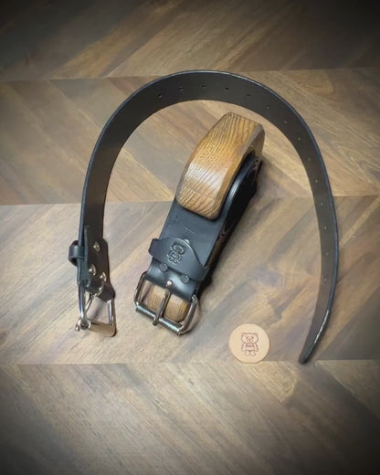 Manual demonstration buckling a heavy 1.75 inch black leather restraints through a steel roller closure.