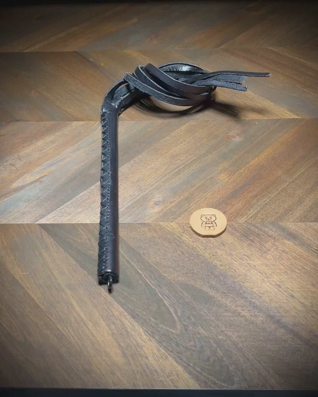 Video showing the dynamic movement and hand-burnished edges of a black leather multi-tail impact crop during a structural reveal sequence.