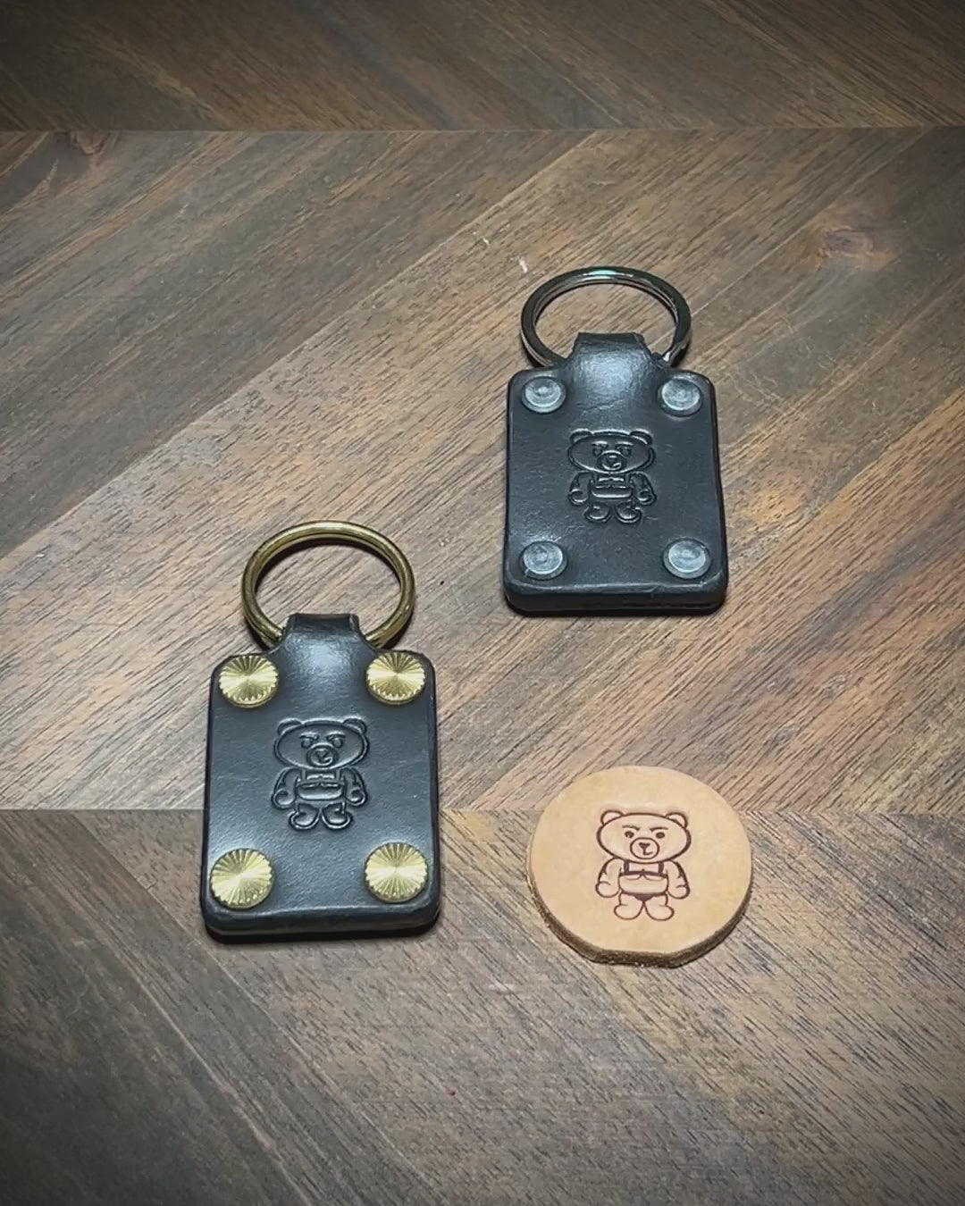 Hand-testing the structural integrity and displaying the hardware variations of two black leather keychains.
