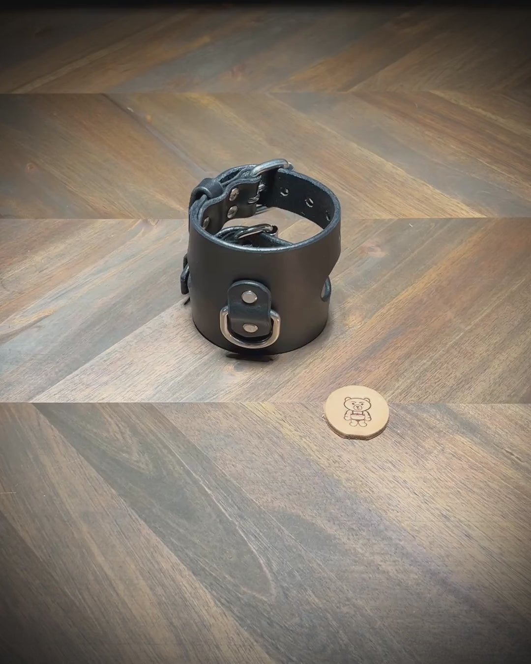 Demonstrating the dual unbuckling action and laying flat of a 3.5" wide black leather restraint cuff with nickel-plated steel hardware.