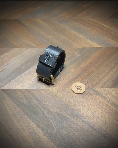 Demonstrating the unbuckling, structural flexibility, interior grain texture, and hardware alignment of a 1.5" black leather cuff with an integrated D-ring.