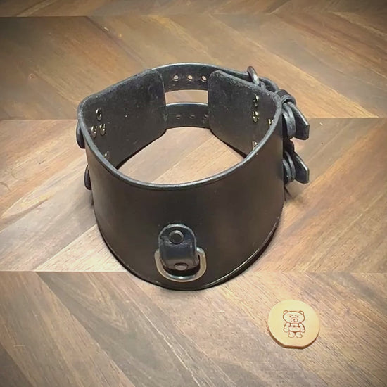 Hand-unbuckling the dual rear closures of a black leather posture collar to demonstrate flexibility and hardware tolerances.