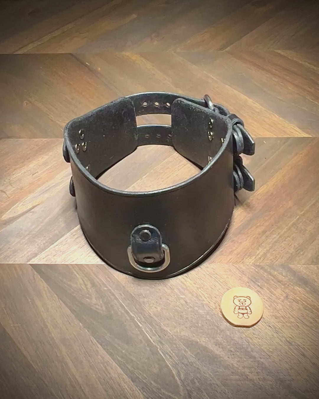 Hand-unbuckling the dual rear closures of a black leather posture collar to demonstrate flexibility and hardware tolerances.