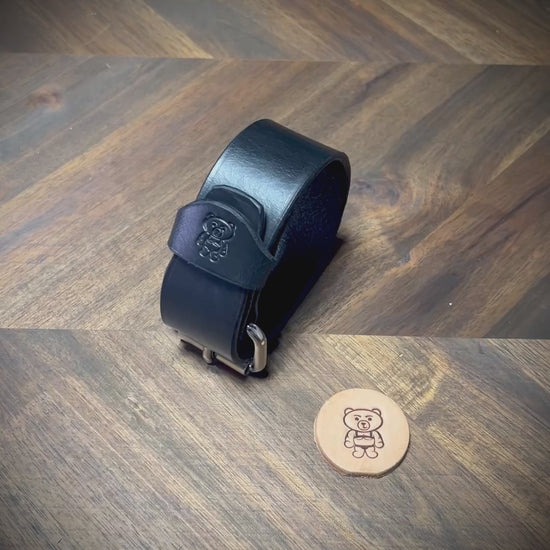 Manual demonstration unbuckling connected 1.25" black leather wrist cuff with steel hardware.