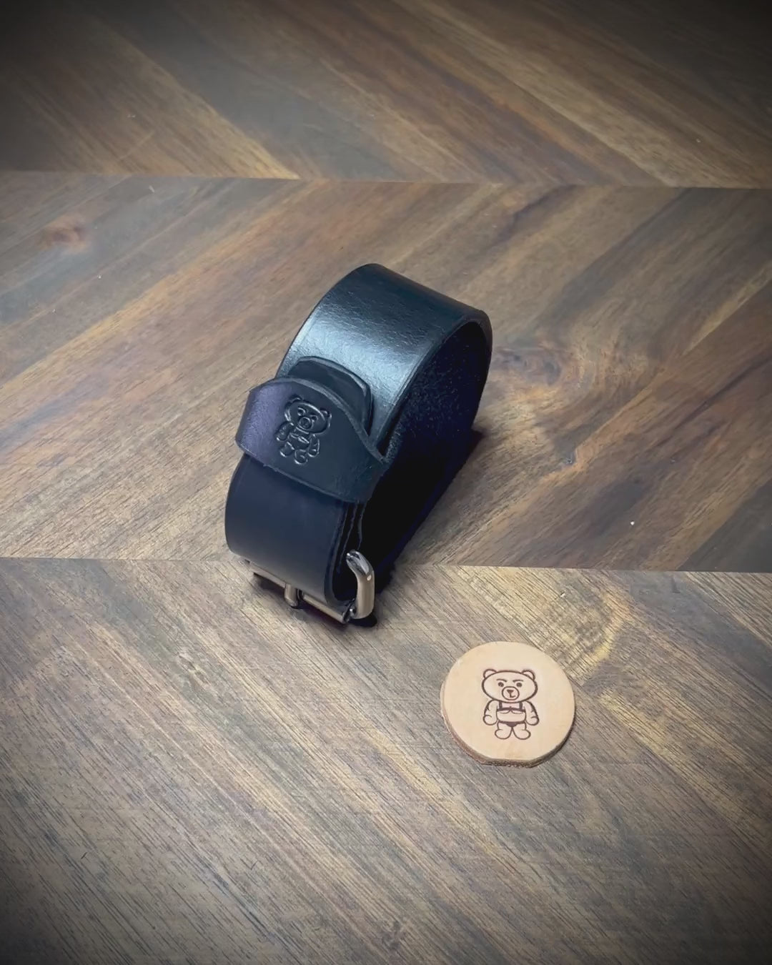 Manual demonstration unbuckling connected 1.25" black leather wrist cuff with steel hardware.