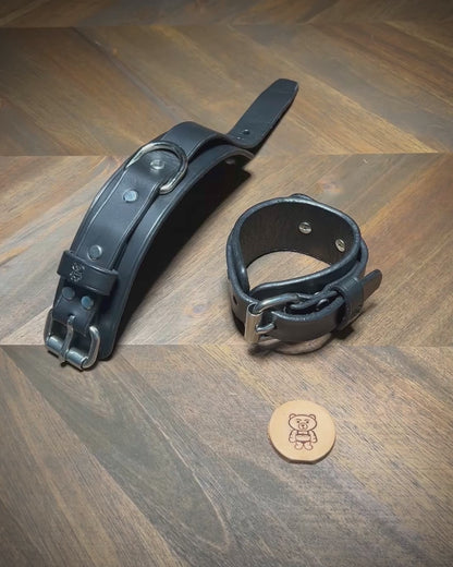 Manually unbuckling a 1.75" wide black leather two-piece cuff to demonstrate hardware operation and dual-layer structural flexibility.