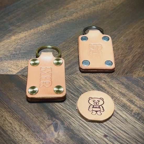 Manual demonstration unfastening screw posts on a personalized natural leather keychain to open the layered body structure.