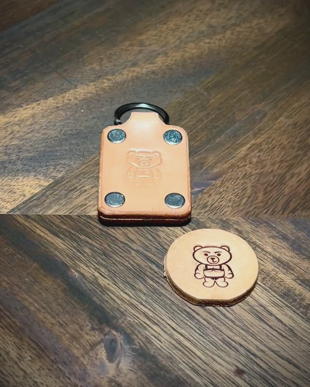 Manual demonstration inspecting edges, nickel hardware, and embossed logo on natural leather keychain.