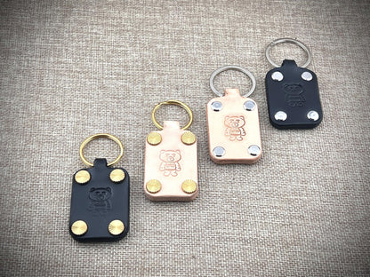 Four keychains with bear emblem on a textured surface