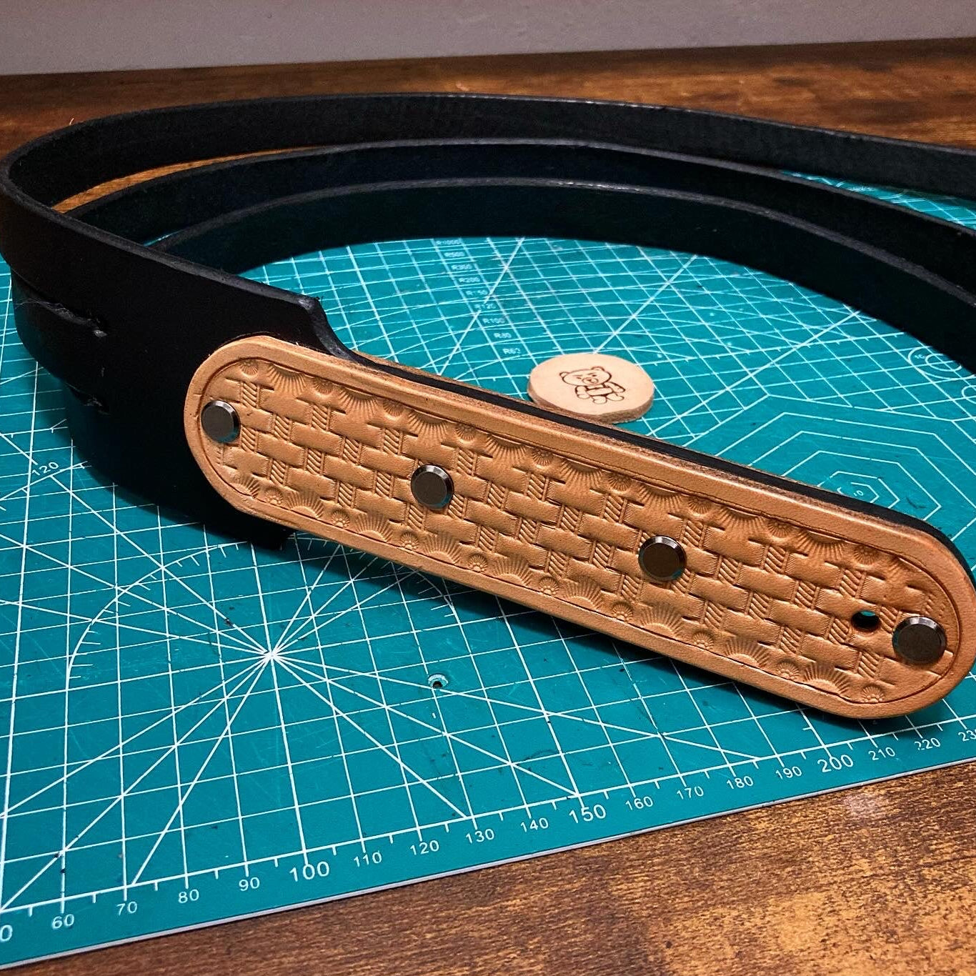 Black belt with woven brown strap on a blue cutting mat