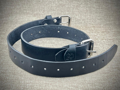 Black leather belts with silver buckle on a textured gray background