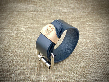 Black leather bracelet with steel buckle on a textured brown background