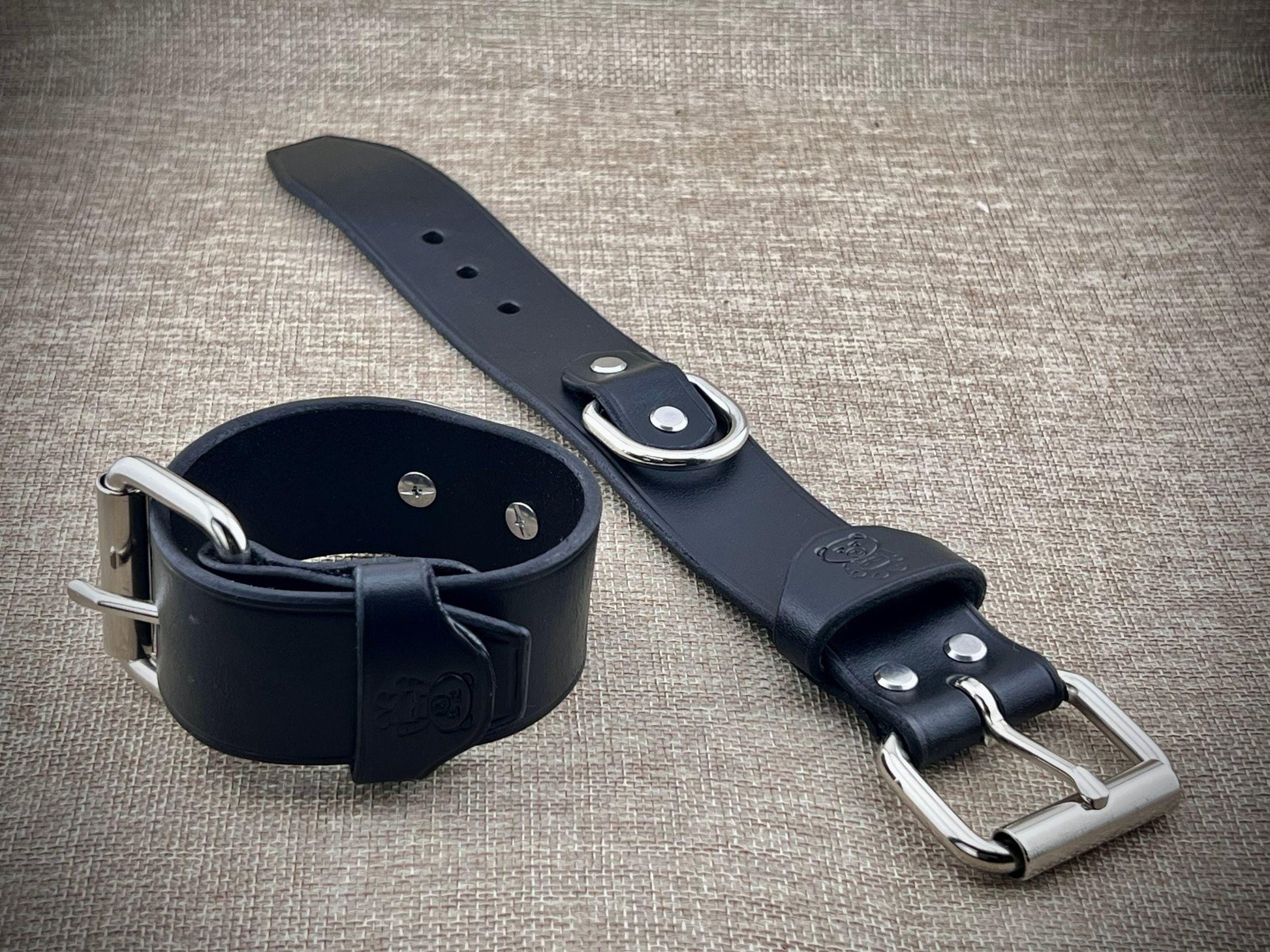 Black leather strap with silver buckles on a textured gray background