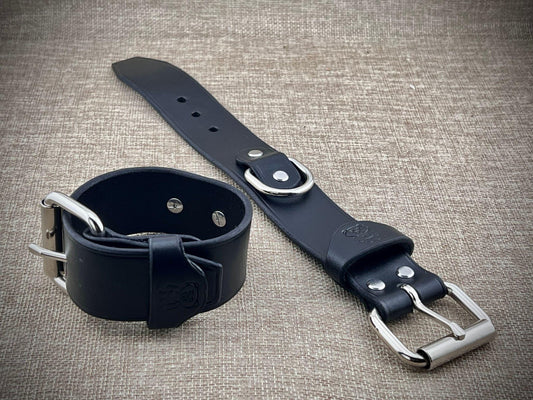 Black leather strap with silver buckles on a textured gray background