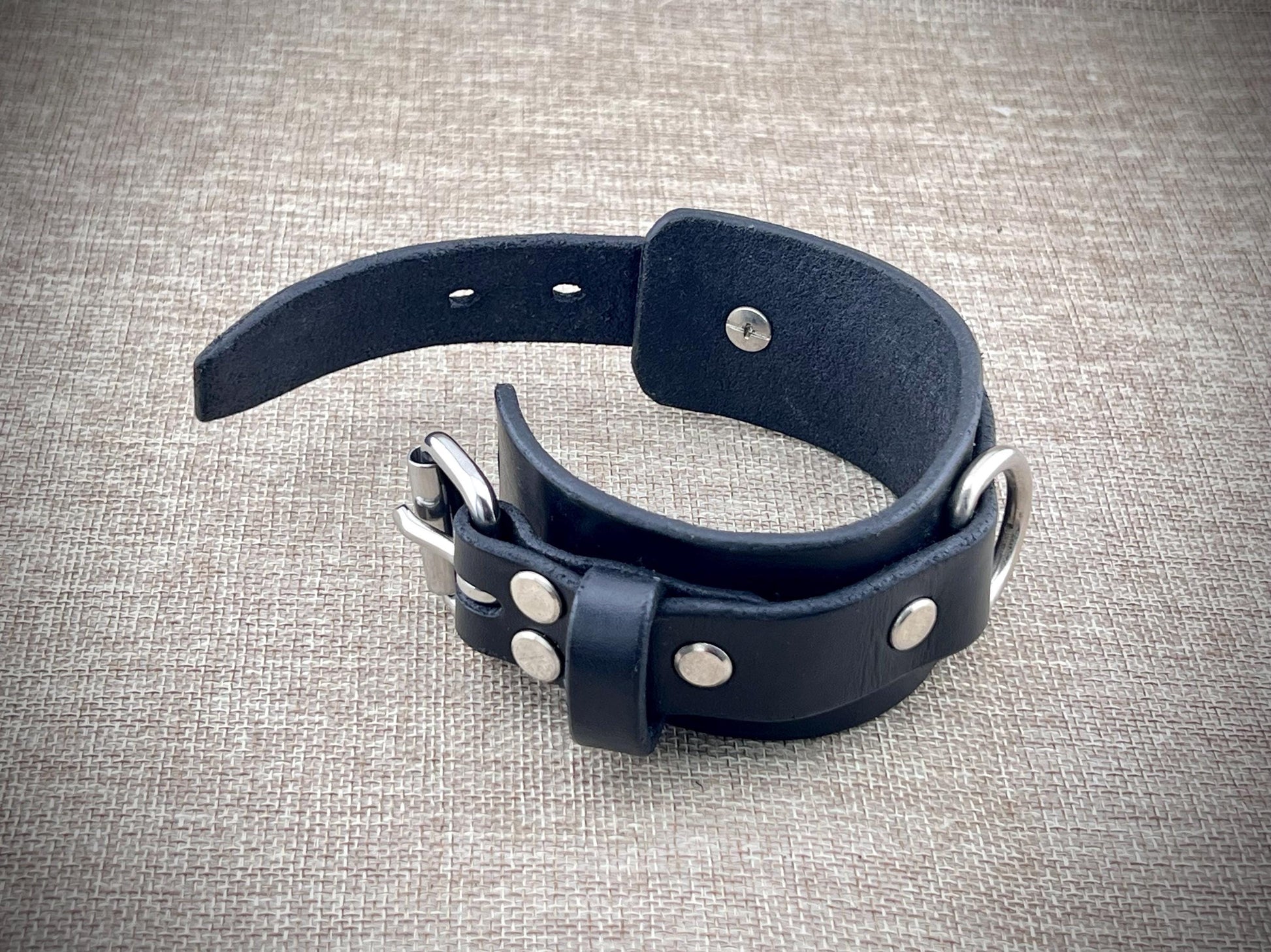 Black leather cuff with silver studs on a textured gray background