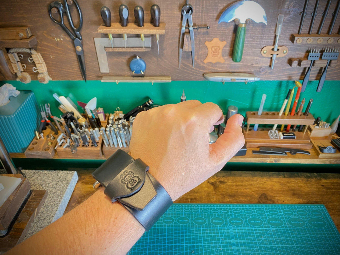 Hand with a watch on a workbench with tools and supplies