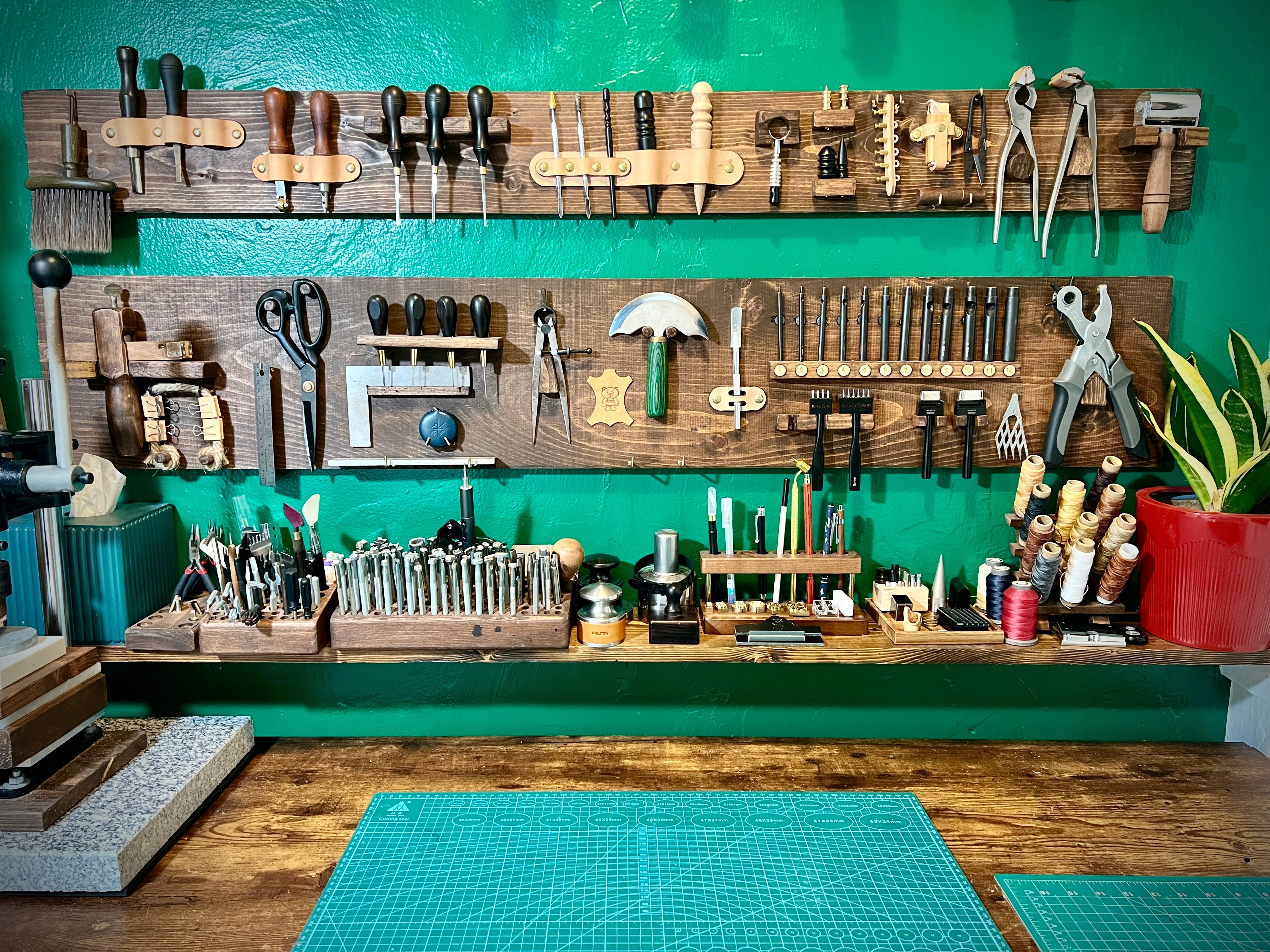 Workshop with tools on a wooden wall rack against a green wall.